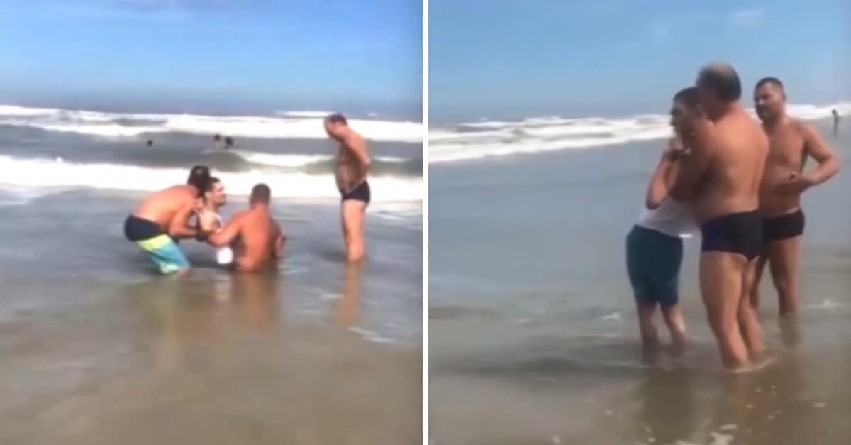 Gli uomini aiutano un papà così suo figlio disabile possa fare il bagno in mare per la prima volta